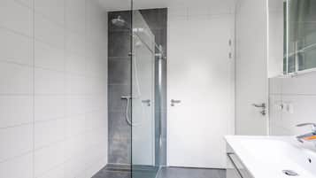 A modern bathroom with a glass-enclosed shower, a white sink, and a large mirror.