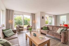 A spacious living area with a sofa, armchairs, a coffee table, and a dining table. - Spacious and Bright 10-person Holiday Villa (De Koog)