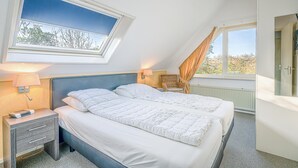 Une chambre avec deux lits, une fenêtre donnant sur un beau paysage, une table de chevet et une chaise.