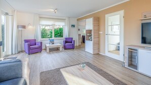 Un salon moderne avec deux fauteuils violets, une table basse et un téléviseur.
