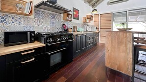 Une cuisine équipée d’une cuisinière, d’un four, d’un four à micro-ondes et d’un îlot central en bois avec un évier.