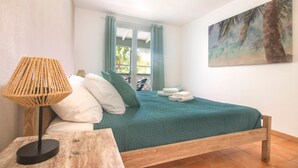 Ein Schlafzimmer mit Bett, Lampe, einem Gemälde und einem Fenster mit Vorhängen.