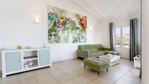 A living room with a green sofa, a white coffee table, and a cabinet with a light blue top. - Timoon, 2 bedroom apartment on the beach with amazing view! (Marigot)
