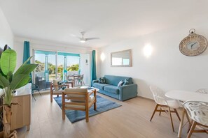 Un salon moderne comprenant un canapé, une table à manger, des chaises et un ventilateur de plafond.