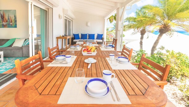 A wooden dining table set with blue and white plates, bowls, and cutlery, surrounded by wooden chairs.