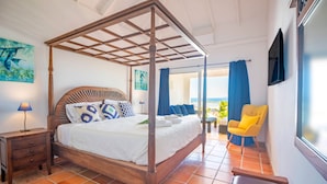 A four-poster bed with a wooden frame, a nightstand with drawers, a lamp, and a chair by the window.
