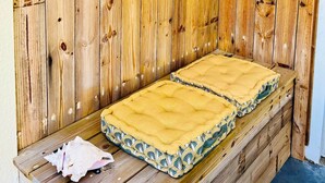 A small, cozy room with a wooden wall, a bed with a yellow bedspread, and decorative macramé wall hangings. - Blue Wave , charming 2 bedrooms, right behind the beach! (Marigot)