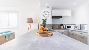 A modern kitchen with a central island, white cabinets, and a microwave. - Blue Wave , charming 2 bedrooms, right behind the beach! (Marigot)