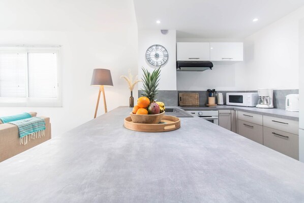 A modern kitchen with a central island, white cabinets, and a microwave.