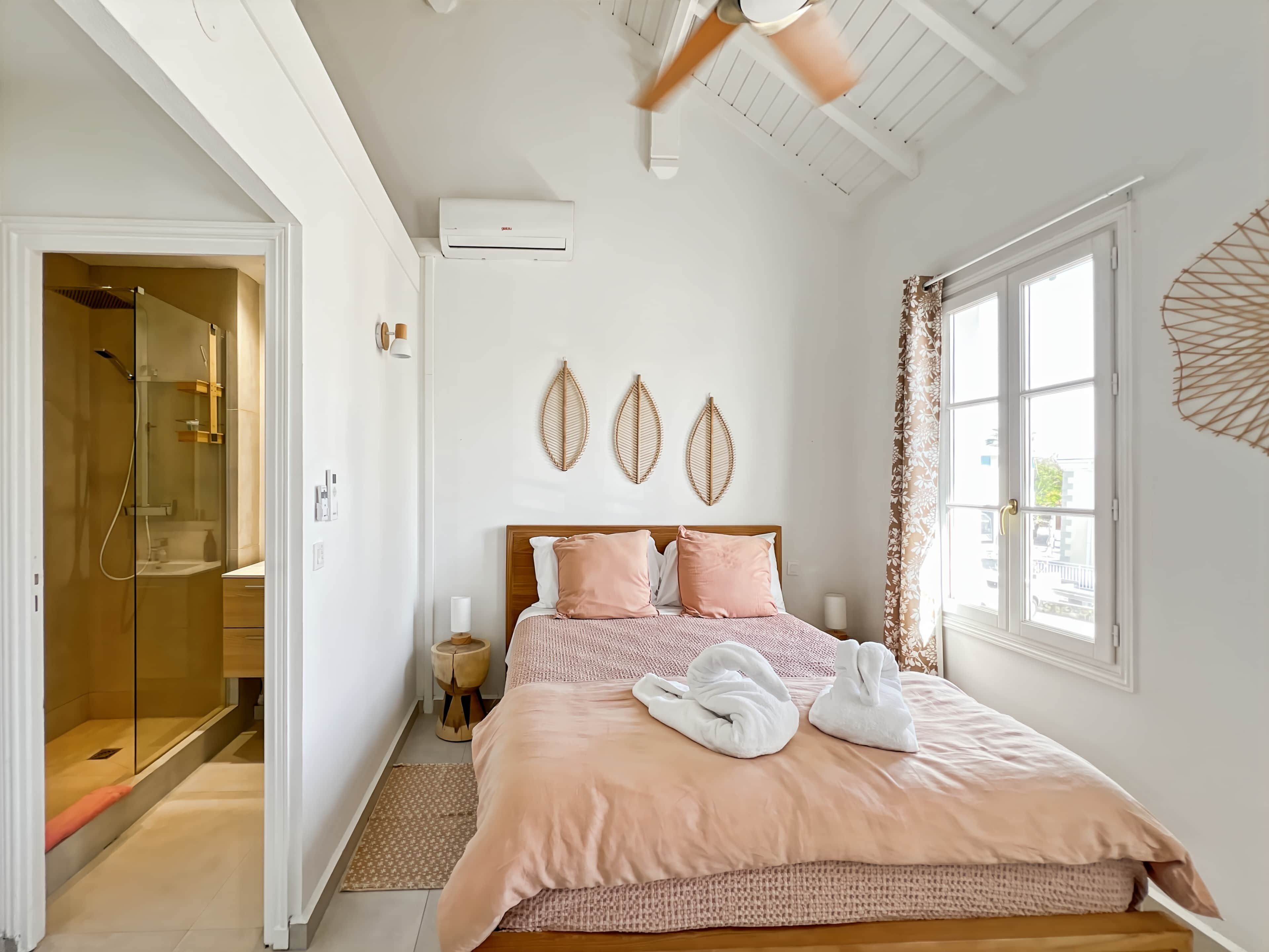 A bedroom with a bed, a window, a ceiling fan, and a wall-mounted air conditioner.
