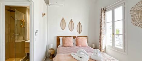 A bedroom with a bed, a window, a ceiling fan, and a wall-mounted air conditioner.