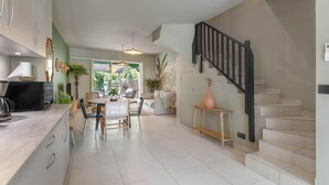 A modern kitchen with a dining area, a staircase, and a view of greenery outside. - Maison GAMA, 2 bedrooms and shared pool (CISTERN!!!) (Collectivity of Saint Martin)