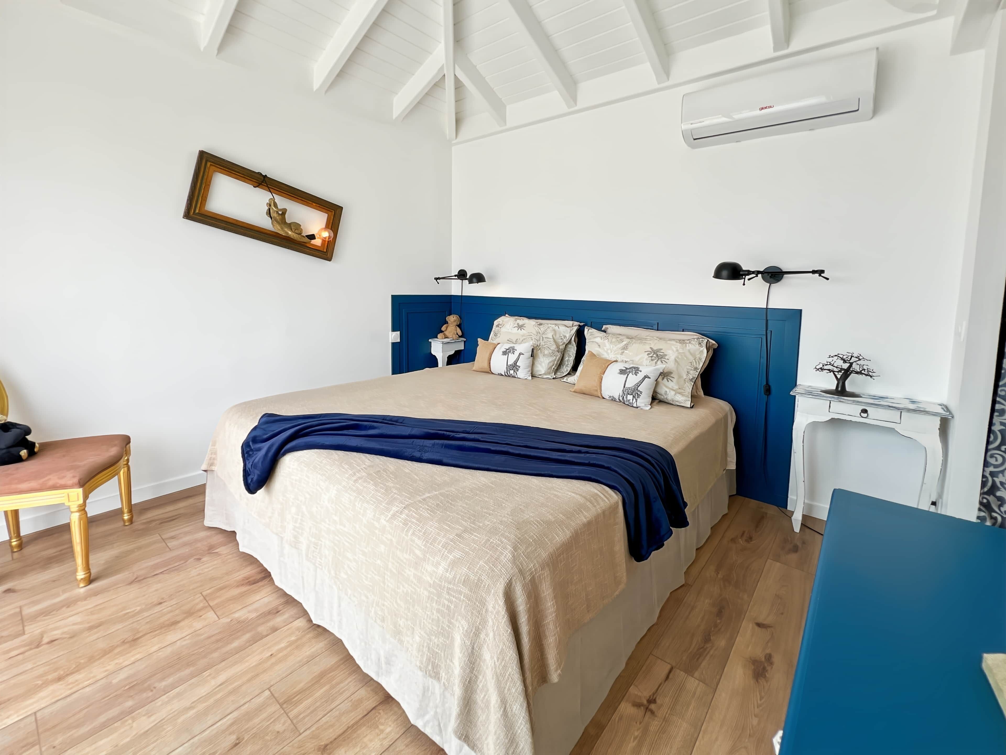 Een slaapkamer met een bed, nachtkastjes, een stoel en een wandairconditioner.