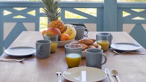 A breakfast table set on a balcony with a view of a building and hills.