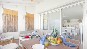 A dining area with a wooden table set for two, a bowl of fruit, and a red bowl.