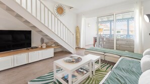 A living room with a TV, sofa, and a staircase.