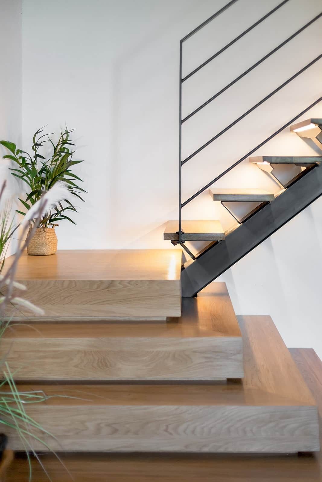 A modern staircase with wooden steps and a metal railing.