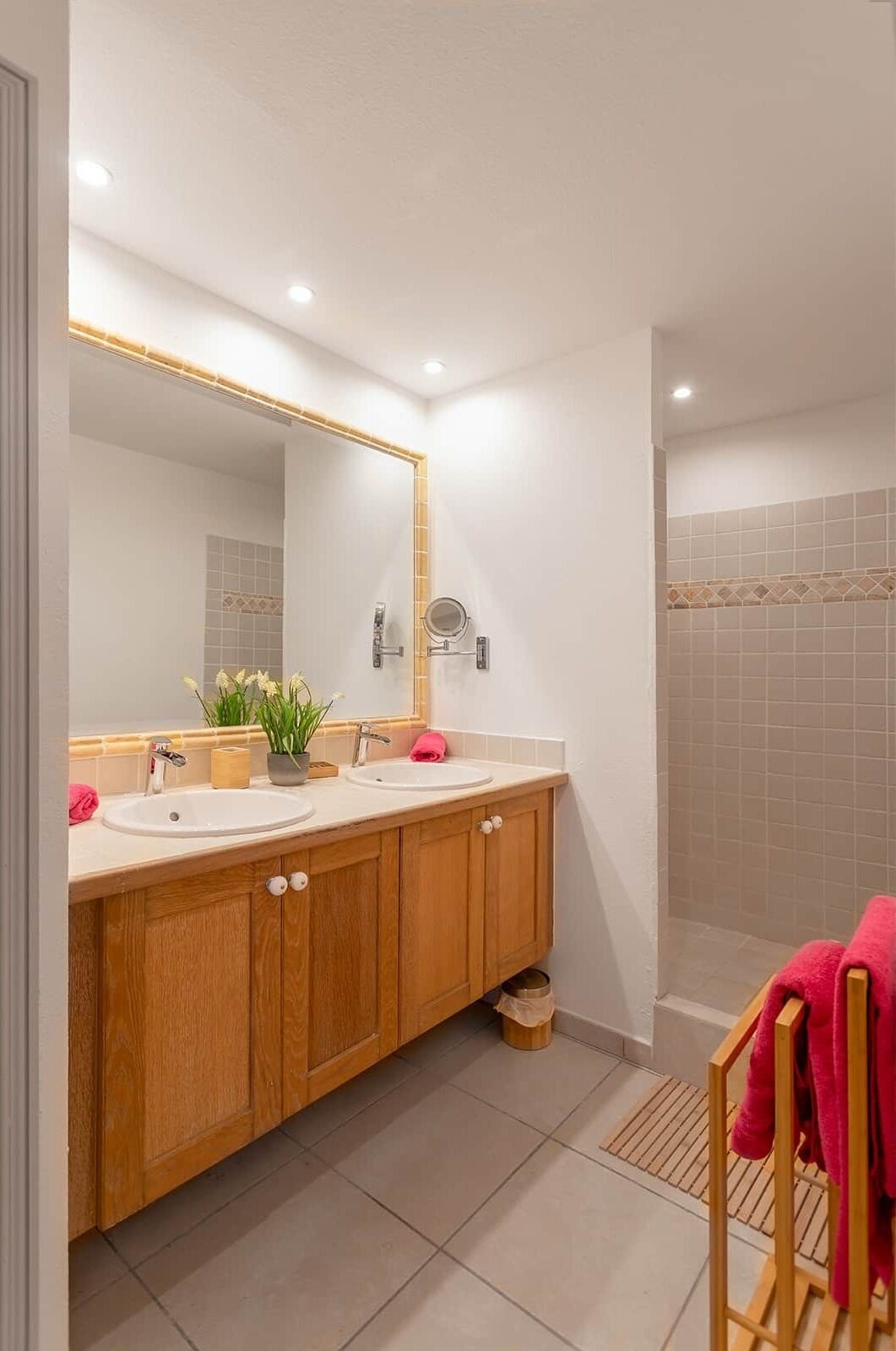 Ein modernes Badezimmer mit zwei Waschbecken, einem großen Spiegel und einer Duschkabine.