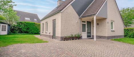A two-story house with a brick exterior, a sloped roof, and a paved driveway.