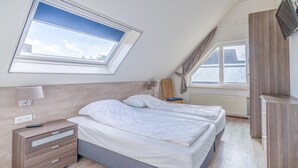 A bedroom with a skylight, a bed, a nightstand, a TV, and a wardrobe. - Charming Villa Near the sea and Forest (De Koog)