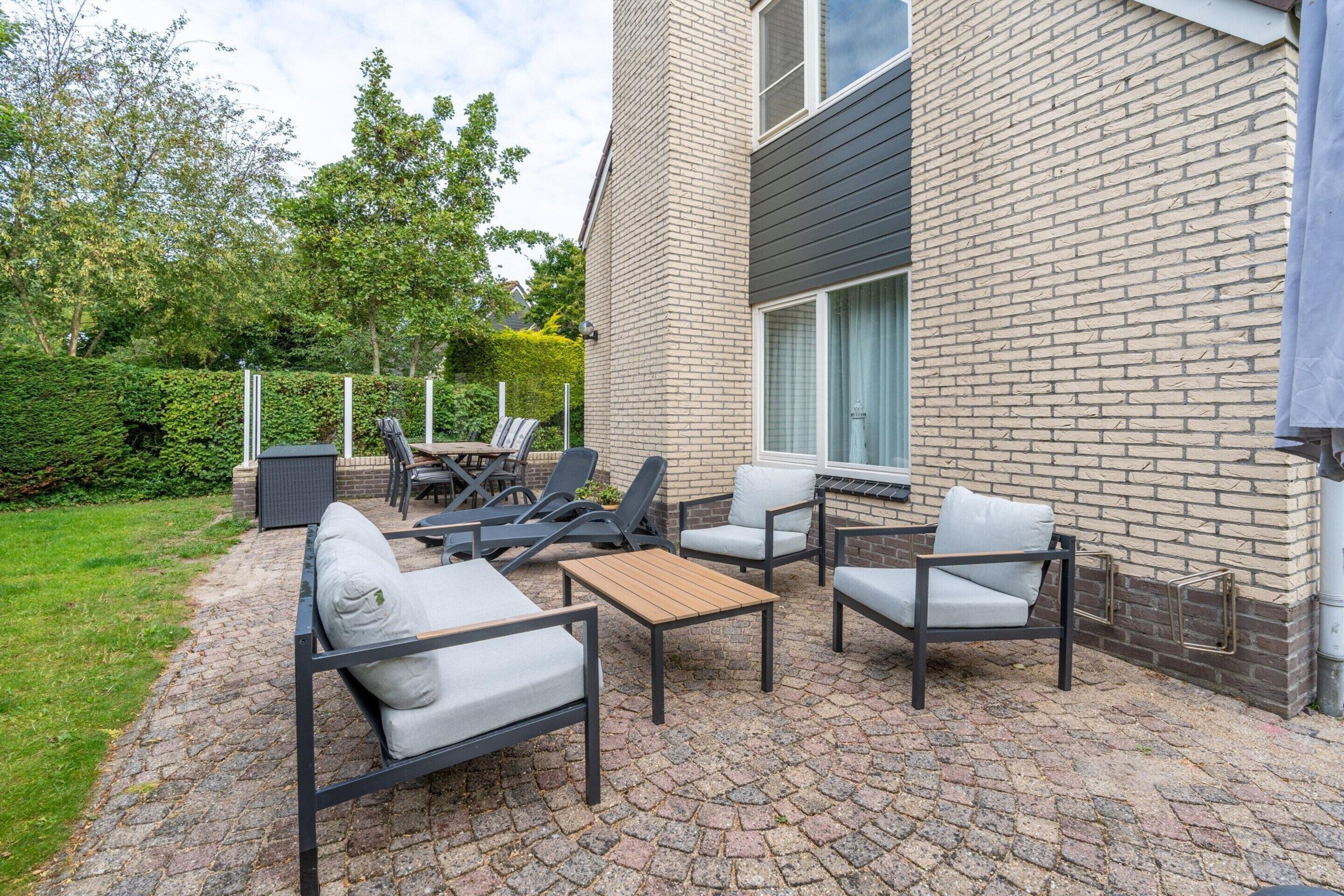 An outdoor patio with a brick wall, seating area, and a view of the surrounding greenery.