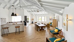 A spacious kitchen with a central island, a dining area with a wooden table and chairs, and a living area with a sofa and cushions. - Villa Mallory, 3 bedrooms, private pool and ocean view (Collectivity of Saint Martin)