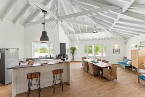 A spacious kitchen with a central island, bar stools, and a dining area with a wooden table and chairs.