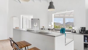 A modern kitchen with a central island, a dining area with wooden chairs, and a view of mountains through large windows. - Villa Mallory, 3 bedrooms, private pool and ocean view (Collectivity of Saint Martin)