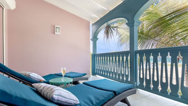 A balcony with two lounge chairs, a small table, and a glass of wine.