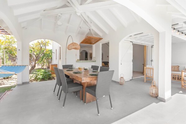 A dining area with a wooden table, grey chairs, and a hanging light fixture.