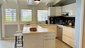 Una cocina moderna con armarios blancos, una isla central, un fregadero y un microondas.