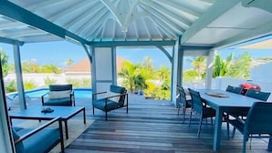 Un espacio al aire libre cubierto con piscina, mobiliario y una parrilla.