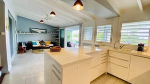Una cocina moderna con una isla grande, armarios blancos e iluminación colgante.