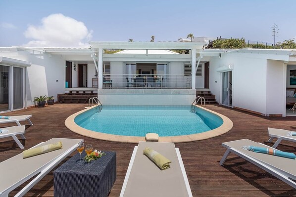 A pool area with lounge chairs and a covered seating area.
