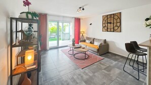 Un salon moderne comprenant un canapé, une table basse et un coin repas avec des chaises.