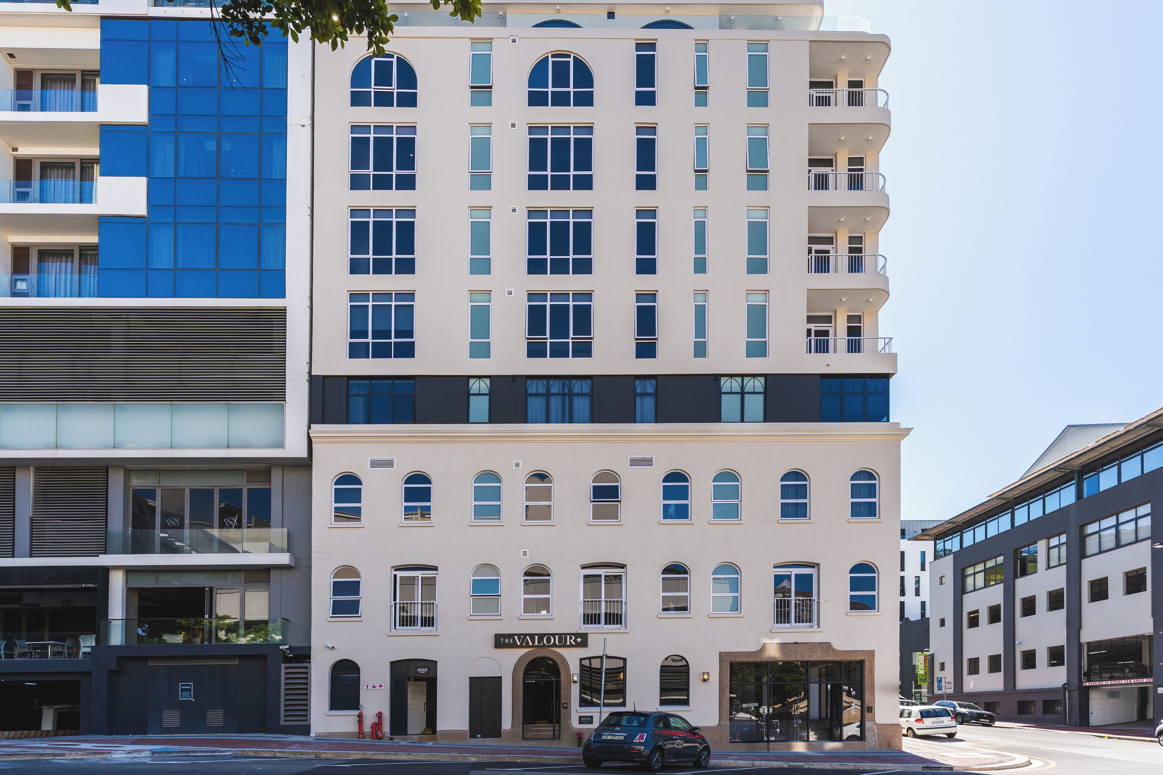 A multi-story hotel with a classic facade, featuring a prominent entrance with a sign reading "The Valour."