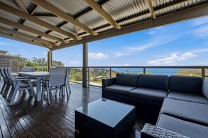 Un espacio al aire libre techado con una mesa, sillas, un sofá y vistas del paisaje.
