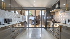 A modern kitchen with stainless steel appliances, a large island, and a sliding glass door leading to a dining area.