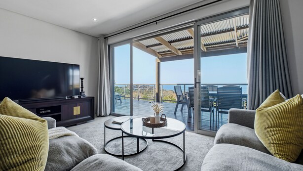 A modern living room with a flat-screen TV, a coffee table, and a sofa. - Simbithi Coastal Escape | Luxury with Ocean Views (Dolphin Coast)