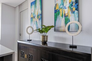 Un interior moderno con un mueble de madera oscura, una planta en maceta y pinturas abstractas en la pared.