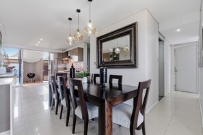 A modern dining room with a large table, chairs, and pendant lighting.