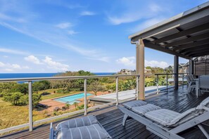 A deck with lounge chairs and a view of a swimming pool and ocean. - Simbithi Coastal Escape | Luxury with Ocean Views (Dolphin Coast)