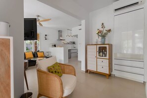 A modern living room with a sofa, a dining area, a kitchen, and a white cabinet with glass doors. - Villa Sunlight (Collectivity of Saint Martin)
