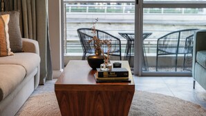 A living room with a wooden coffee table, a sofa, and a view of outdoor seating. - Harbour Bridge Retreat | No Loadshedding (Cape Town)