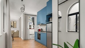 A modern kitchen with blue cabinets, a stainless steel refrigerator, and a wooden herringbone floor. - Venice-Inspired Penthouse with City Views (Cape Town)