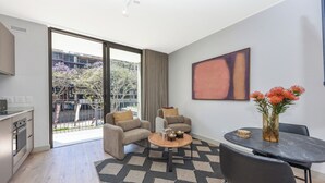 Una sala de estar moderna con un sofá, una mesa de centro y una mesa de comedor. Hay un ventanal que ofrece vistas al exterior.