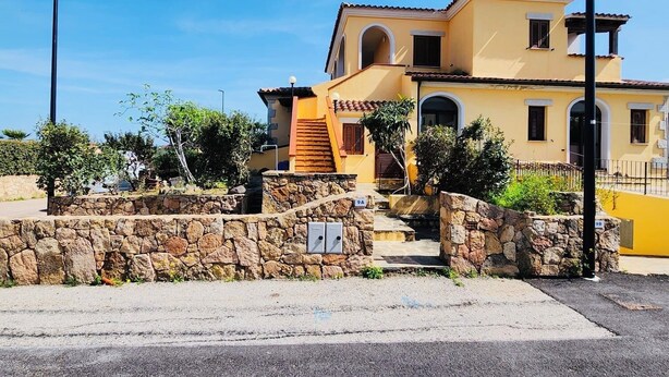 Un bâtiment jaune à deux étages, doté d’une entrée en pierre, d’un escalier et surplombant un ciel d’un bleu éclatant.