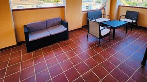 Un balcon avec un canapé, deux fauteuils et une petite table.