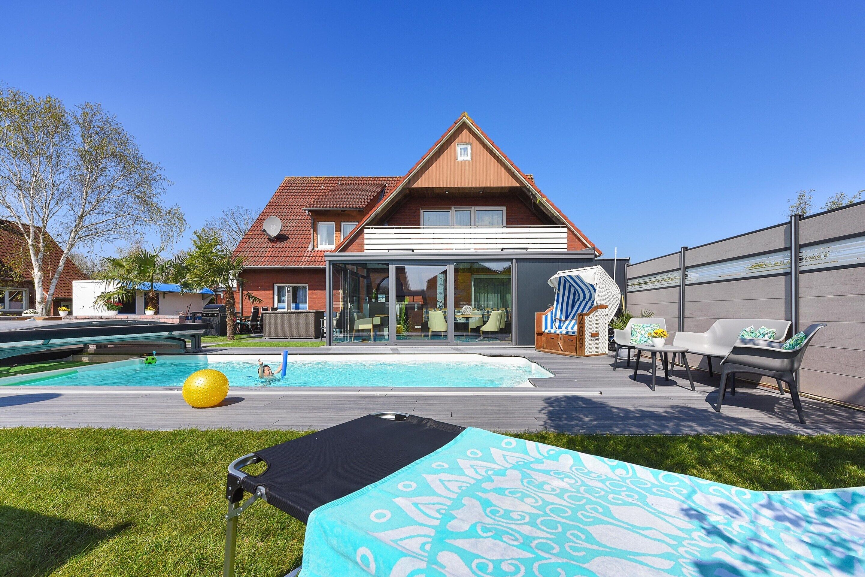 Una casa con piscina, arredi da esterno e un patio.