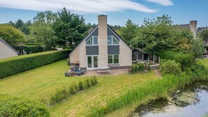 Een modern huis met een ruime voortuin, een zwembad en een goed onderhouden tuin.